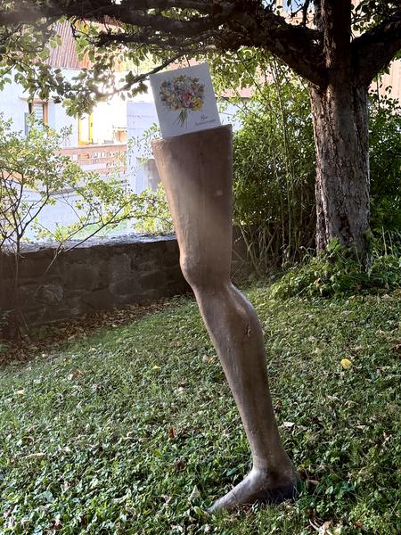 A unique bronze sculpture of a leg stands prominently in a lush green garden at Chemin de Fontaine Noire, Les Allues